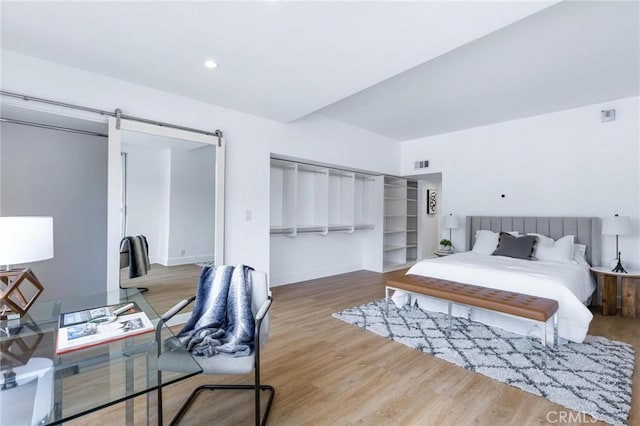 bedroom with hardwood / wood-style flooring and a barn door