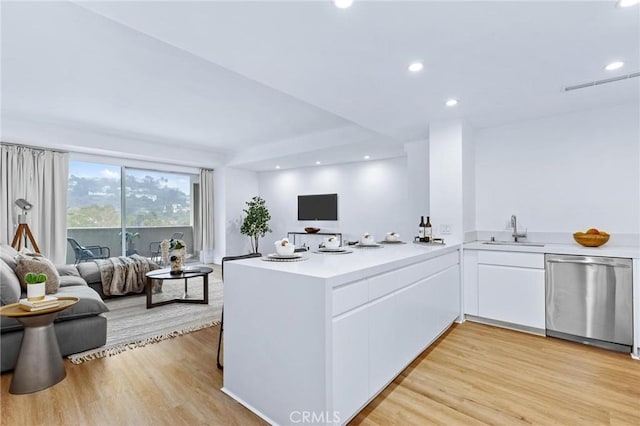 kitchen with sink, light wood-type flooring, stainless steel dishwasher, kitchen peninsula, and white cabinets