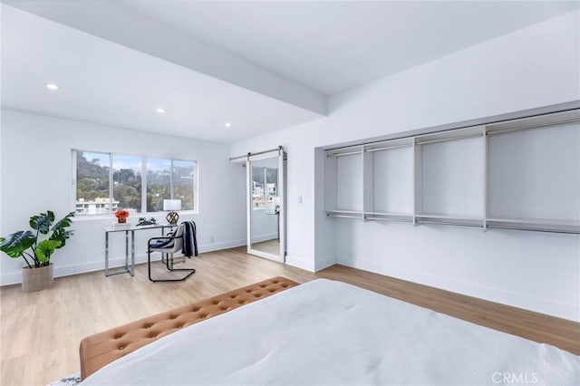 bedroom featuring a barn door and light hardwood / wood-style floors