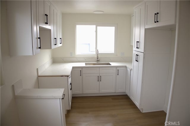 kitchen featuring light hardwood / wood-style floors, sink, and white cabinets