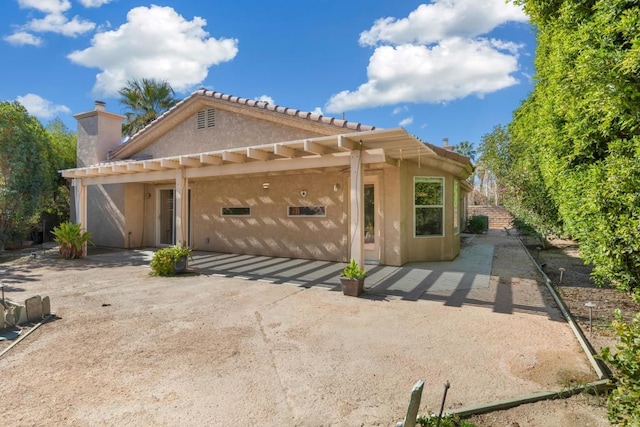 back of property featuring a garage and a pergola