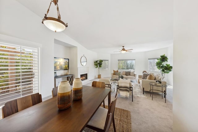 carpeted dining space with a fireplace, ceiling fan, and vaulted ceiling