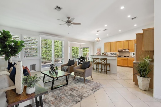 tiled living room featuring lofted ceiling and ceiling fan with notable chandelier