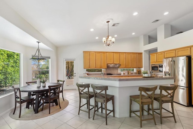 kitchen with pendant lighting, decorative backsplash, an island with sink, and appliances with stainless steel finishes