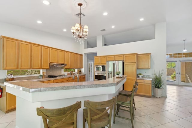 kitchen featuring decorative light fixtures, a breakfast bar area, stainless steel appliances, and a large island with sink