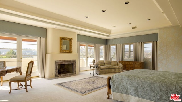 bedroom with multiple windows, a premium fireplace, light colored carpet, and french doors