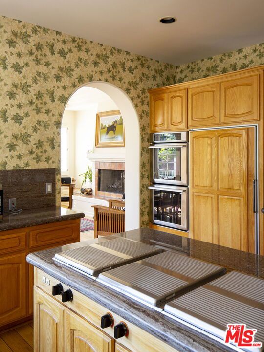 kitchen featuring double oven, a tile fireplace, and light hardwood / wood-style floors