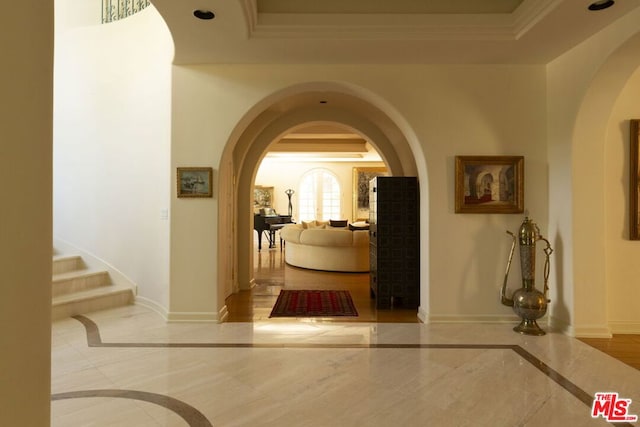 hall with ornamental molding and a tray ceiling