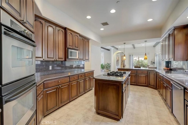 kitchen with tasteful backsplash, stainless steel appliances, pendant lighting, a kitchen island, and kitchen peninsula