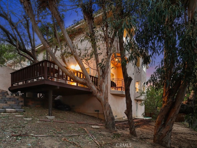 back house at dusk with a wooden deck