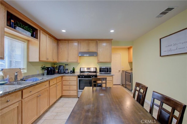 kitchen with light brown cabinetry, sink, light stone counters, stainless steel appliances, and washer and clothes dryer