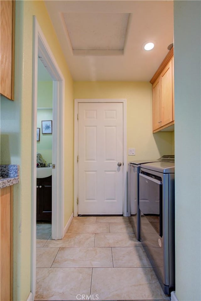 laundry room featuring cabinets, light tile patterned flooring, and washing machine and clothes dryer