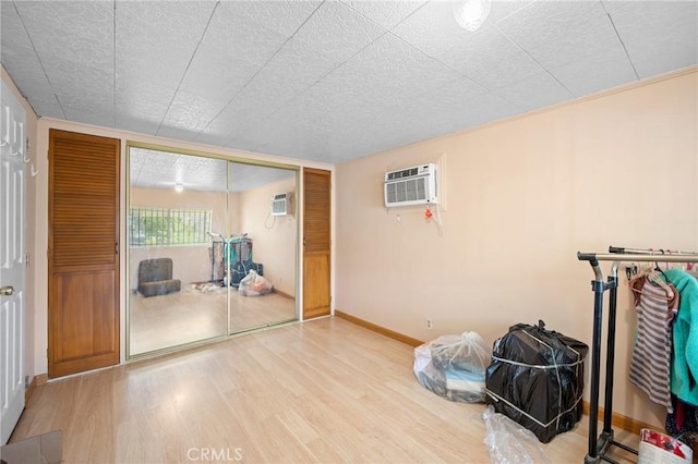 interior space with an AC wall unit, a textured ceiling, and light wood-type flooring