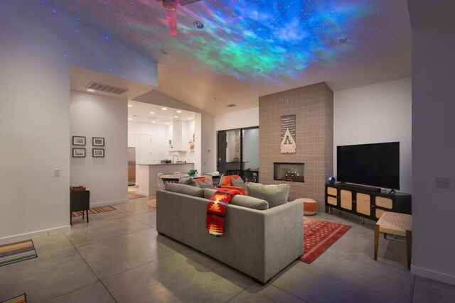 living room featuring a tile fireplace, vaulted ceiling, and concrete floors