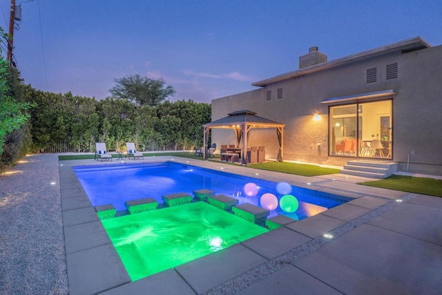 pool at dusk with a gazebo and a patio area