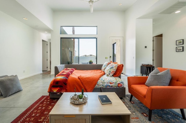 bedroom featuring concrete flooring and a high ceiling