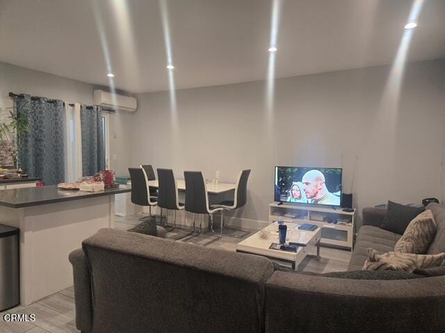 living room with a wall unit AC and light hardwood / wood-style flooring