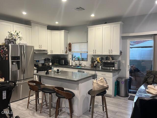 kitchen featuring appliances with stainless steel finishes, a breakfast bar, white cabinets, and decorative backsplash