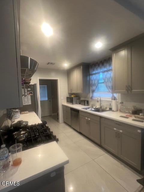 kitchen with gray cabinetry, sink, stainless steel appliances, and light tile patterned flooring