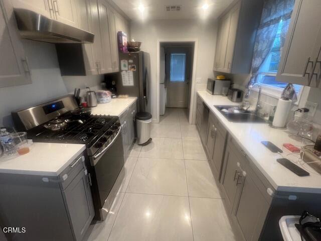 kitchen featuring sink, gray cabinets, gas stove, and light tile patterned floors