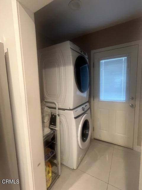 clothes washing area featuring stacked washer / drying machine and light tile patterned floors