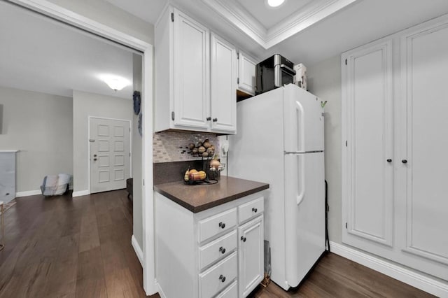 kitchen with tasteful backsplash, white cabinetry, white fridge, a tray ceiling, and dark wood-type flooring