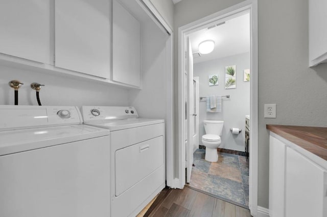 washroom featuring cabinets, dark hardwood / wood-style flooring, and washer and clothes dryer