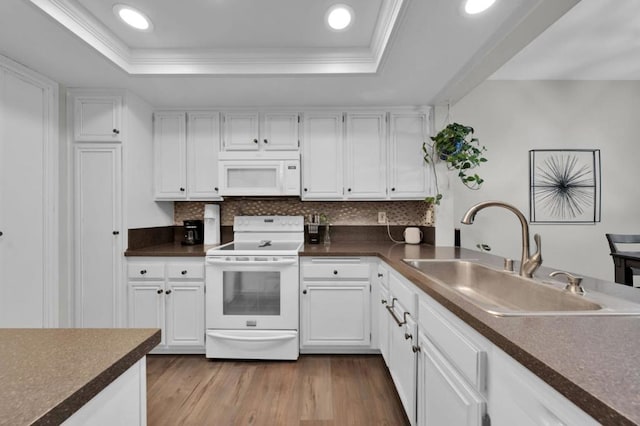 kitchen featuring a raised ceiling, sink, white cabinets, and white appliances