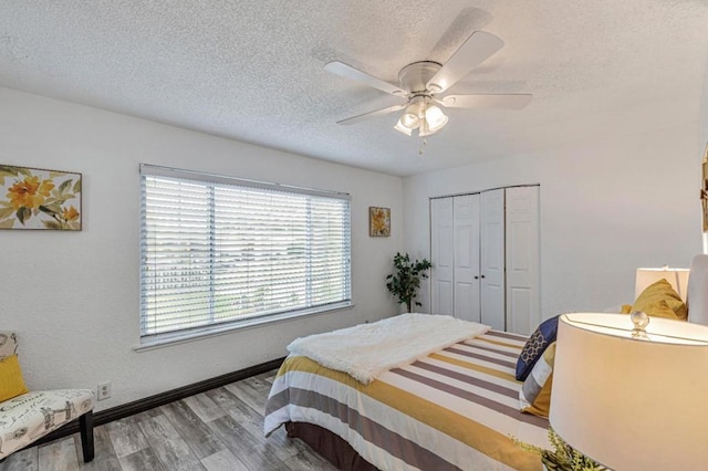 bedroom featuring ceiling fan, wood-type flooring, a closet, and a textured ceiling