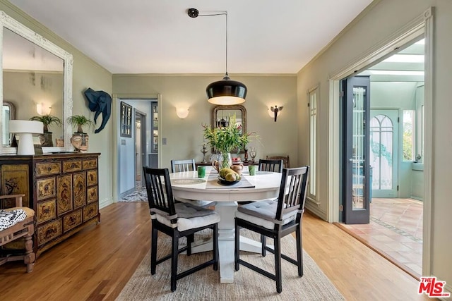 dining room with ornamental molding and light hardwood / wood-style flooring