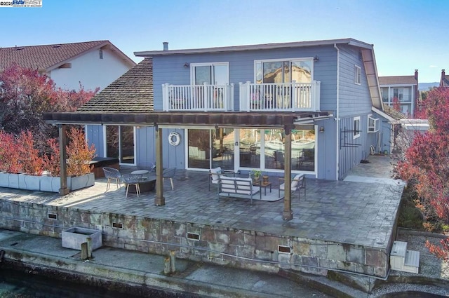 back of property featuring an outdoor living space, a patio, and a balcony