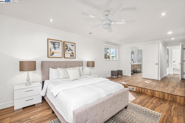 bedroom with ceiling fan, ornamental molding, connected bathroom, and hardwood / wood-style floors