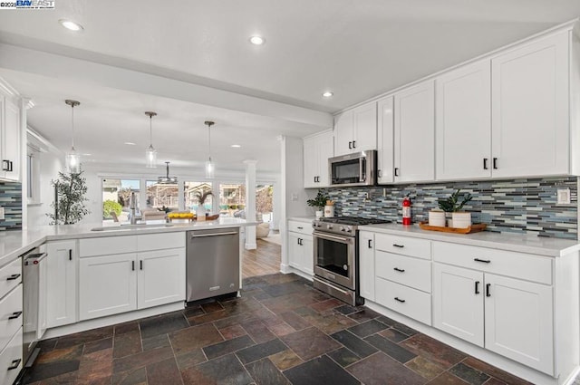 kitchen with white cabinetry, appliances with stainless steel finishes, sink, and decorative light fixtures