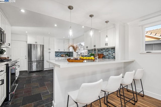 kitchen featuring white cabinetry, stainless steel appliances, kitchen peninsula, and decorative backsplash