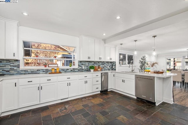 kitchen featuring white cabinetry, hanging light fixtures, stainless steel dishwasher, and kitchen peninsula