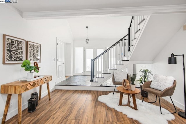 entrance foyer featuring hardwood / wood-style flooring, ornamental molding, and vaulted ceiling