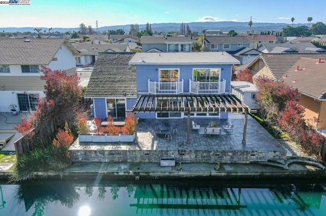 back of house featuring a patio area, a water and mountain view, and a balcony