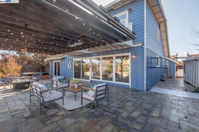 view of patio featuring a jacuzzi and an outdoor living space with a fire pit