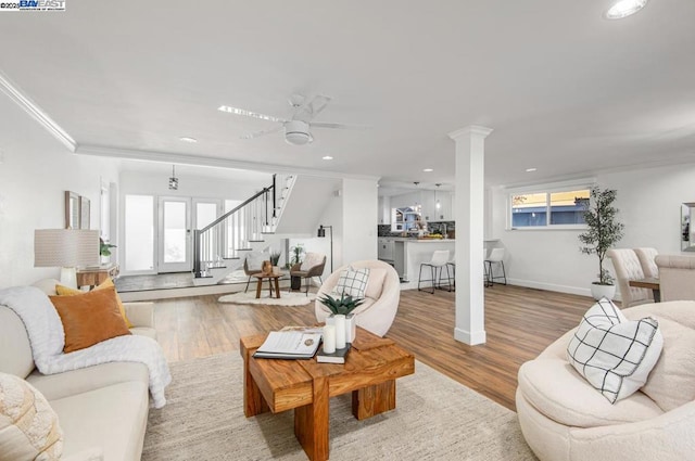 living room featuring hardwood / wood-style flooring, ornamental molding, a wealth of natural light, and ornate columns