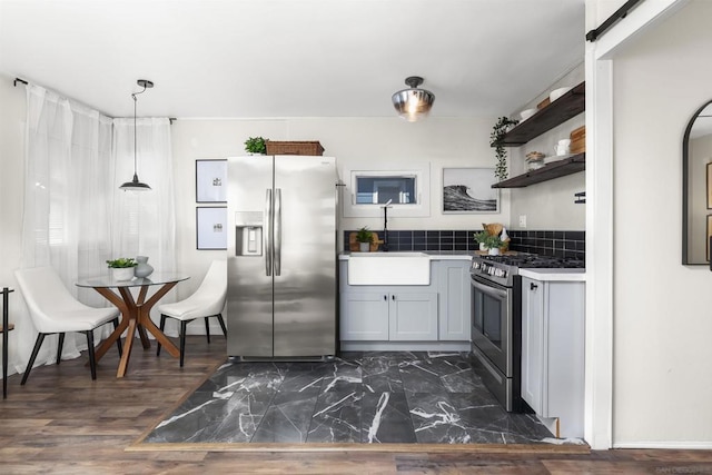 kitchen with pendant lighting, sink, gray cabinets, appliances with stainless steel finishes, and wall chimney exhaust hood