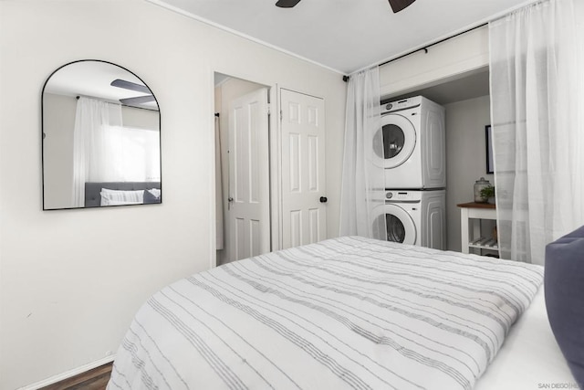 bedroom featuring stacked washer and dryer and ceiling fan