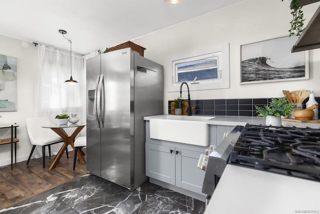 kitchen featuring gray cabinets, decorative light fixtures, tasteful backsplash, sink, and stainless steel fridge