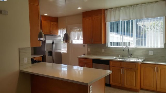 kitchen featuring appliances with stainless steel finishes, tasteful backsplash, sink, hanging light fixtures, and kitchen peninsula