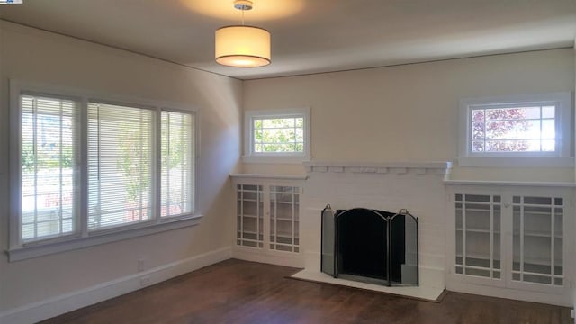 unfurnished living room with a brick fireplace, a wealth of natural light, and dark hardwood / wood-style floors