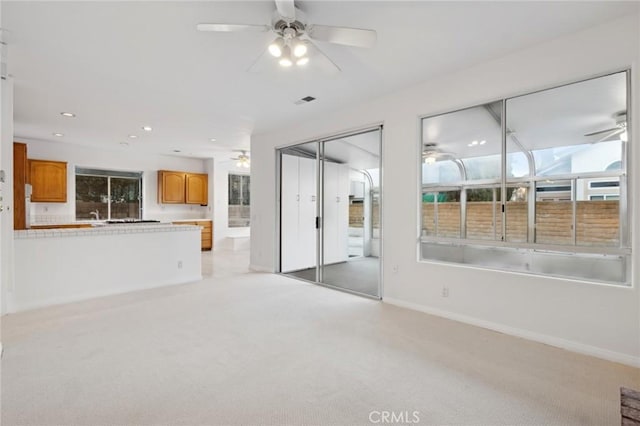 unfurnished living room featuring light carpet and ceiling fan