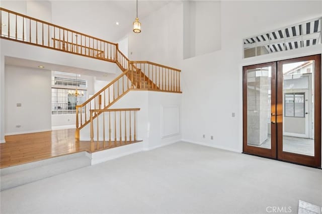 unfurnished living room with a wealth of natural light, a chandelier, and a high ceiling