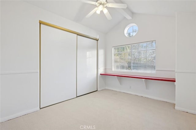 unfurnished bedroom with light carpet, lofted ceiling with beams, a closet, and ceiling fan