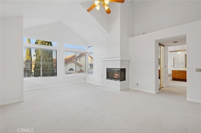 unfurnished living room featuring light carpet, high vaulted ceiling, a tile fireplace, and ceiling fan