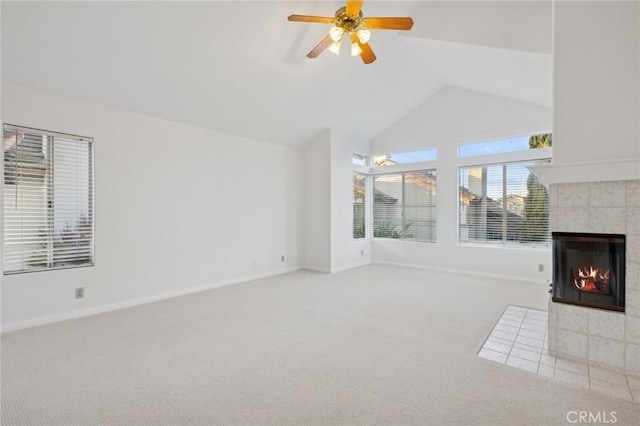 unfurnished living room with a tiled fireplace, carpet, high vaulted ceiling, and ceiling fan