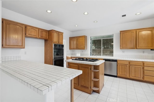 kitchen featuring tile counters, a kitchen island, kitchen peninsula, and appliances with stainless steel finishes